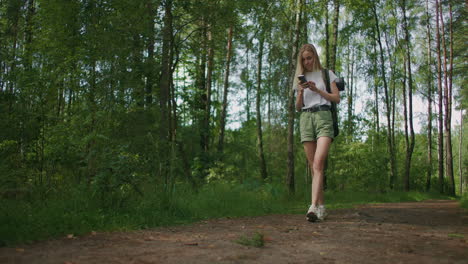 General-plan-mobile-phone-in-the-hands-of-a-female-traveler-walking-through-the-forest.-Social-networks-Navigator-and-messenger.-Use-your-mobile-phone-for-a-walk-in-the-woods